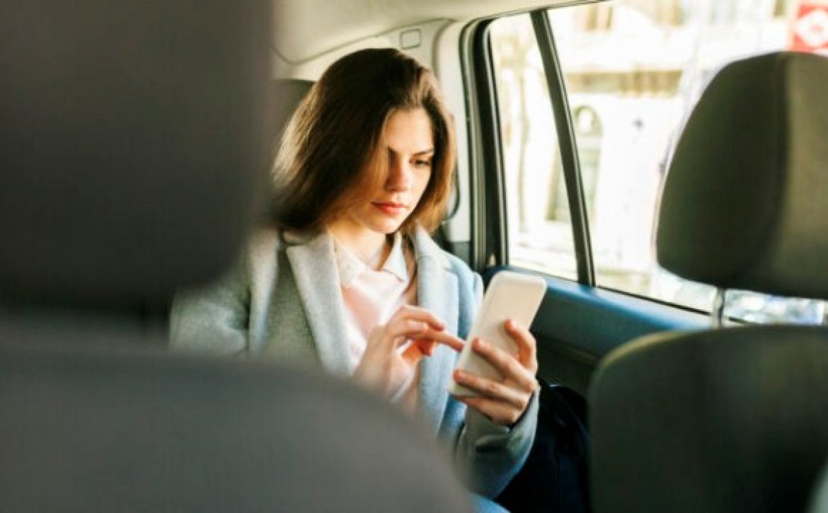 Young businesswoman sitting on backseat of a car using cell phone