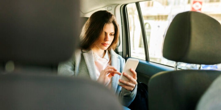 Young businesswoman sitting on backseat of a car using cell phone