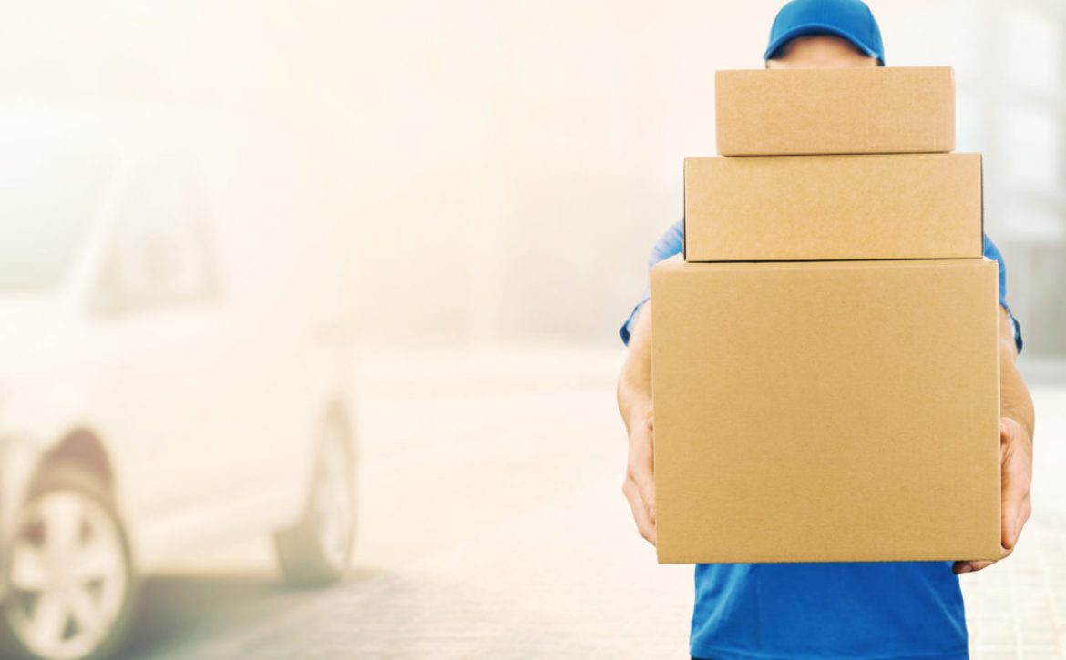 delivery man holding pile of cardboard boxes in front